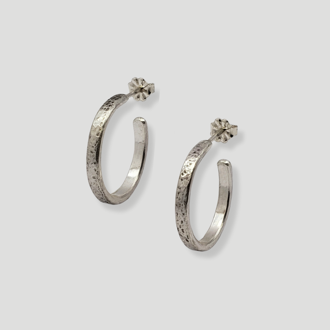 Left facing silver hoop earrings against gray background 