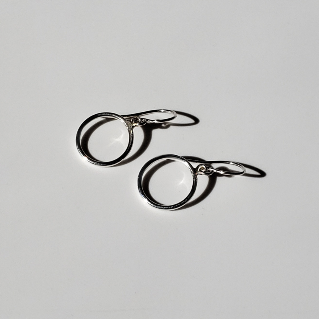 Small silver hoop earrings on beige background