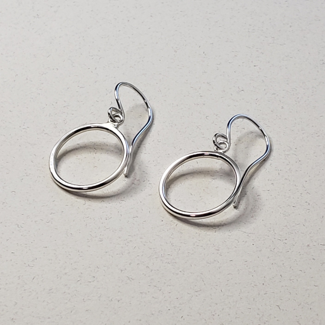 Small silver hoop earrings on beige background 