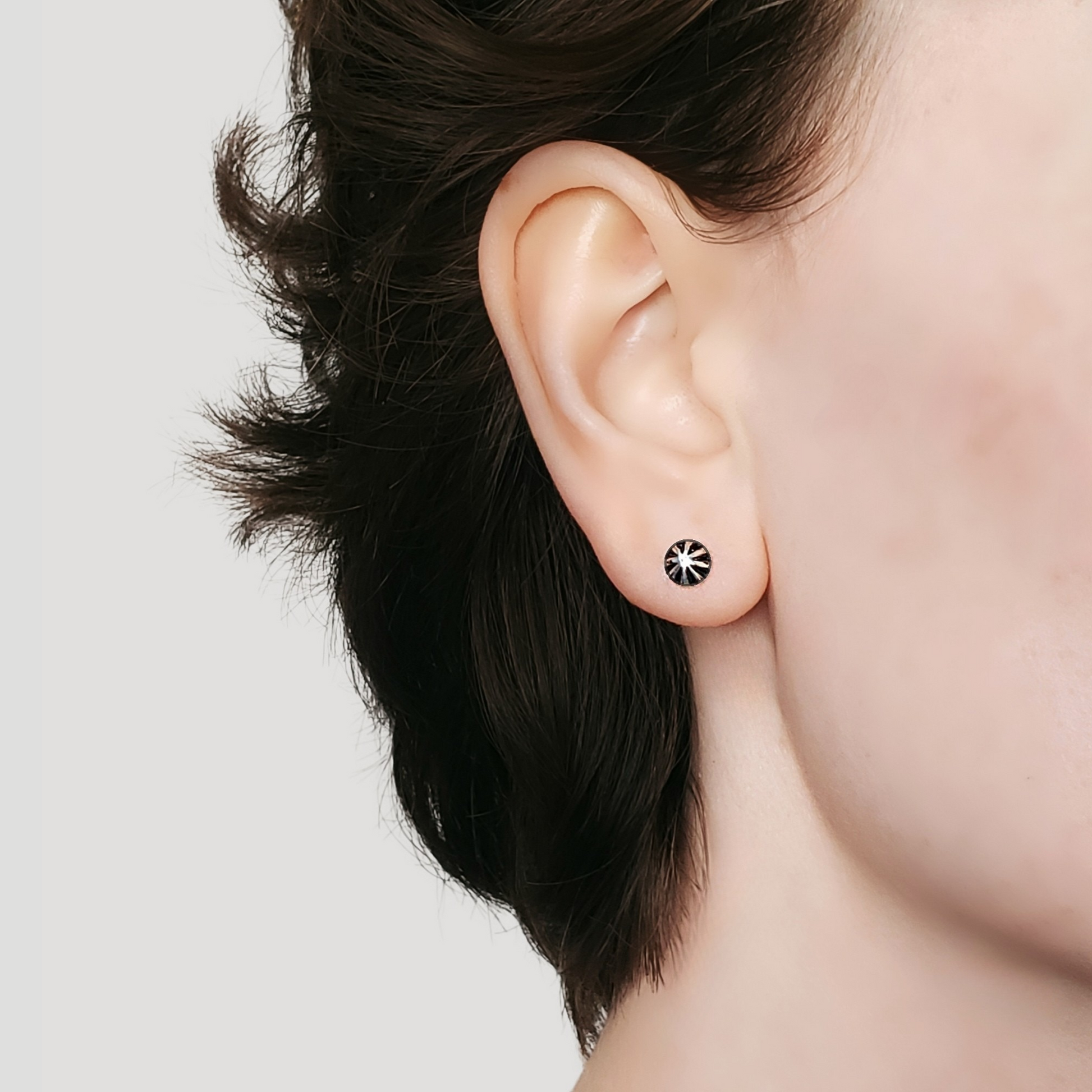 Image of a right facing model wearing a pair of small silver stud earrings