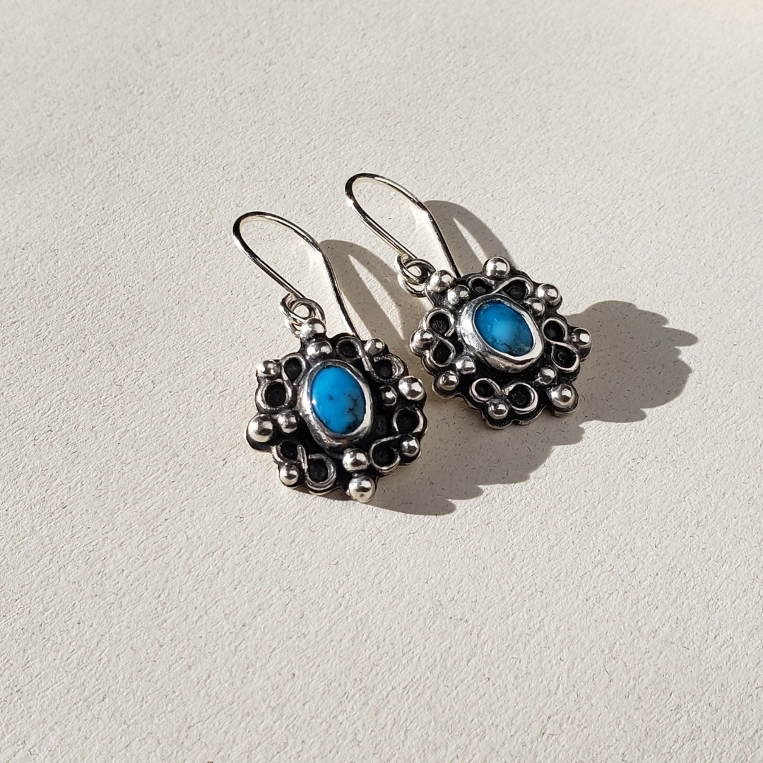 Bright blue Kingman turquoise stones set in handmade sterling silver settings accented with small silver scrolls and silver studs.