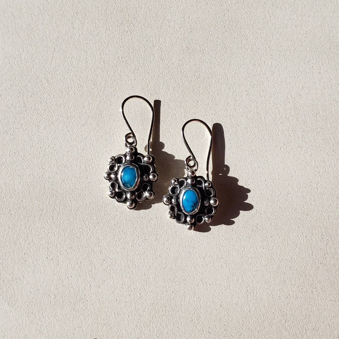 Bright blue Kingman turquoise stones set in handmade sterling silver settings accented with small silver scrolls and silver studs. These handmade turquoise earrings measure 1.25" in length by half inch wide.