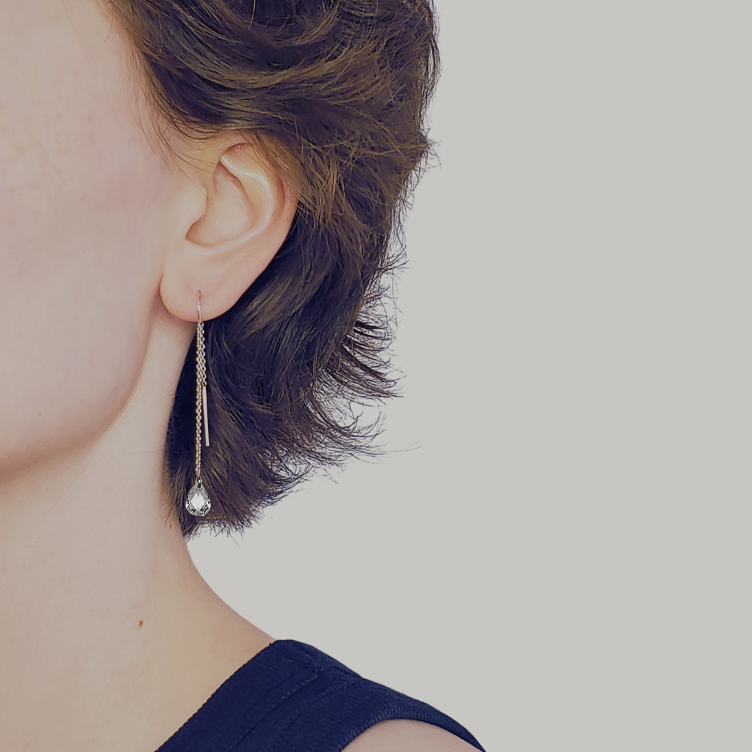 Image of left facing model head wearing long silver threader earrings with a teardrop cubic zirconia briolette drop.