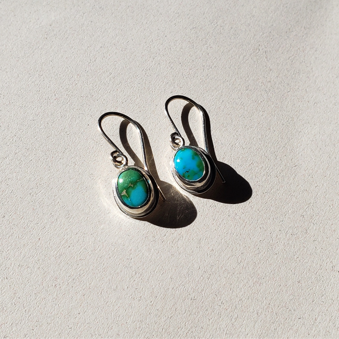 Turquoise drop earrings against a beige background 