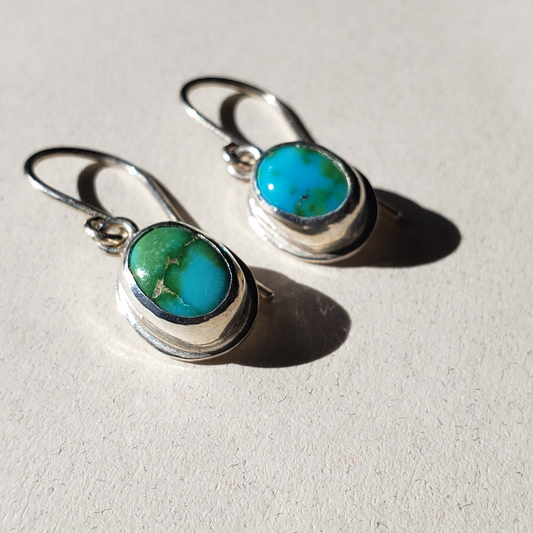 Turquoise drop earrings against a beige background