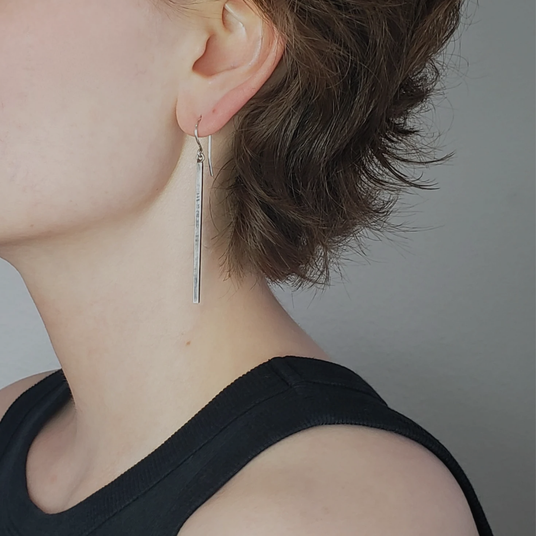 Long sterling silver bar earrings on sterling silver wires. These long silver earrings are accented with gentle handmade texture and black patina finish. These silver drop earrings measure 2" in length and are perfect for everyday wear