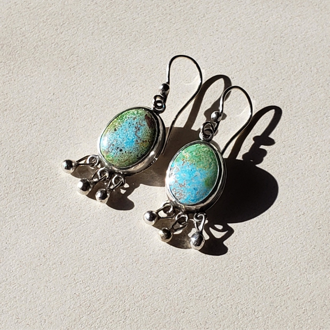 This is a beautiful pair of large oval turquoise earrings with three small round ball dangles across the bottom of the earrings. They are all handmade from sterling silver and hung from handmade sterling silver wires. These large turquoise earrings measure one and a half inches long and are half inch wide.