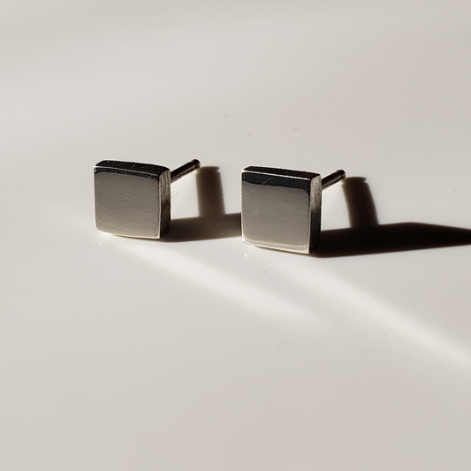 Small handcrafted sterling silver square stud earrings against white background. 