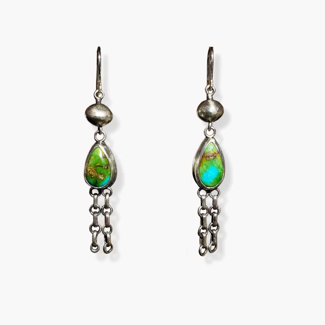 Long turquoise earrings against white background 