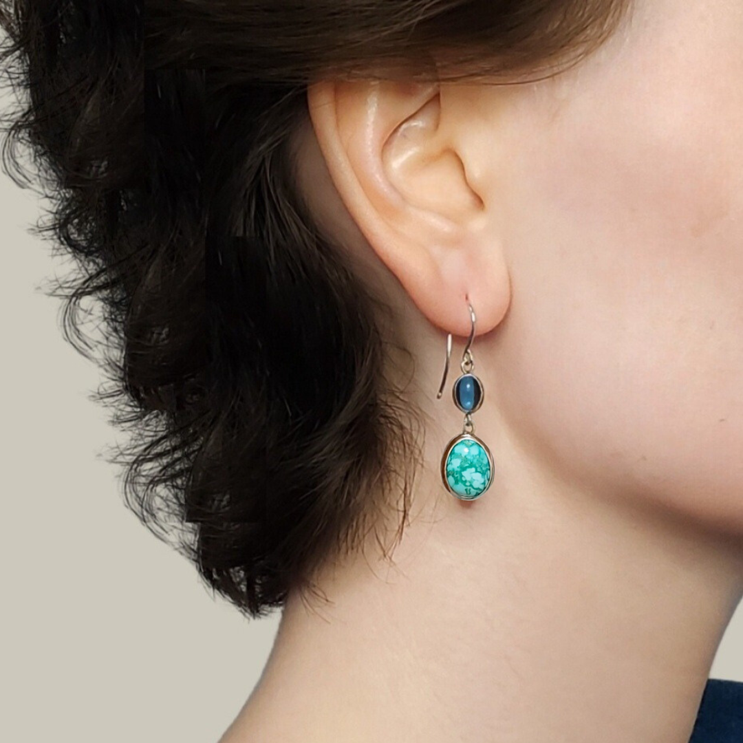 Right facing woman with blue turquoise earrings against white background 