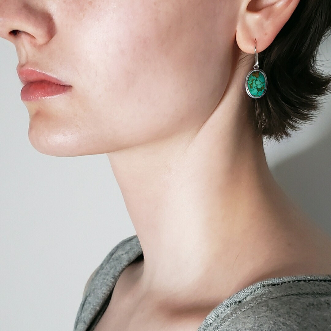 Left facing model wearing green turquoise earrings 