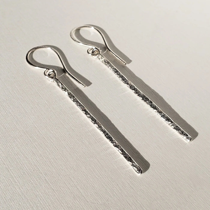 Long silver bar earrings with hammered texture hung on sterling ear wires