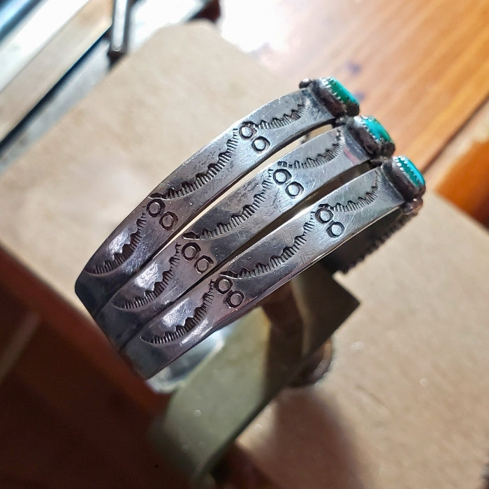 Three silver bracelets with turquoise stones on a wooden surface