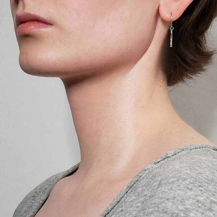 Left facing woman wearing hammered sterling silver bar earrings hung from wires