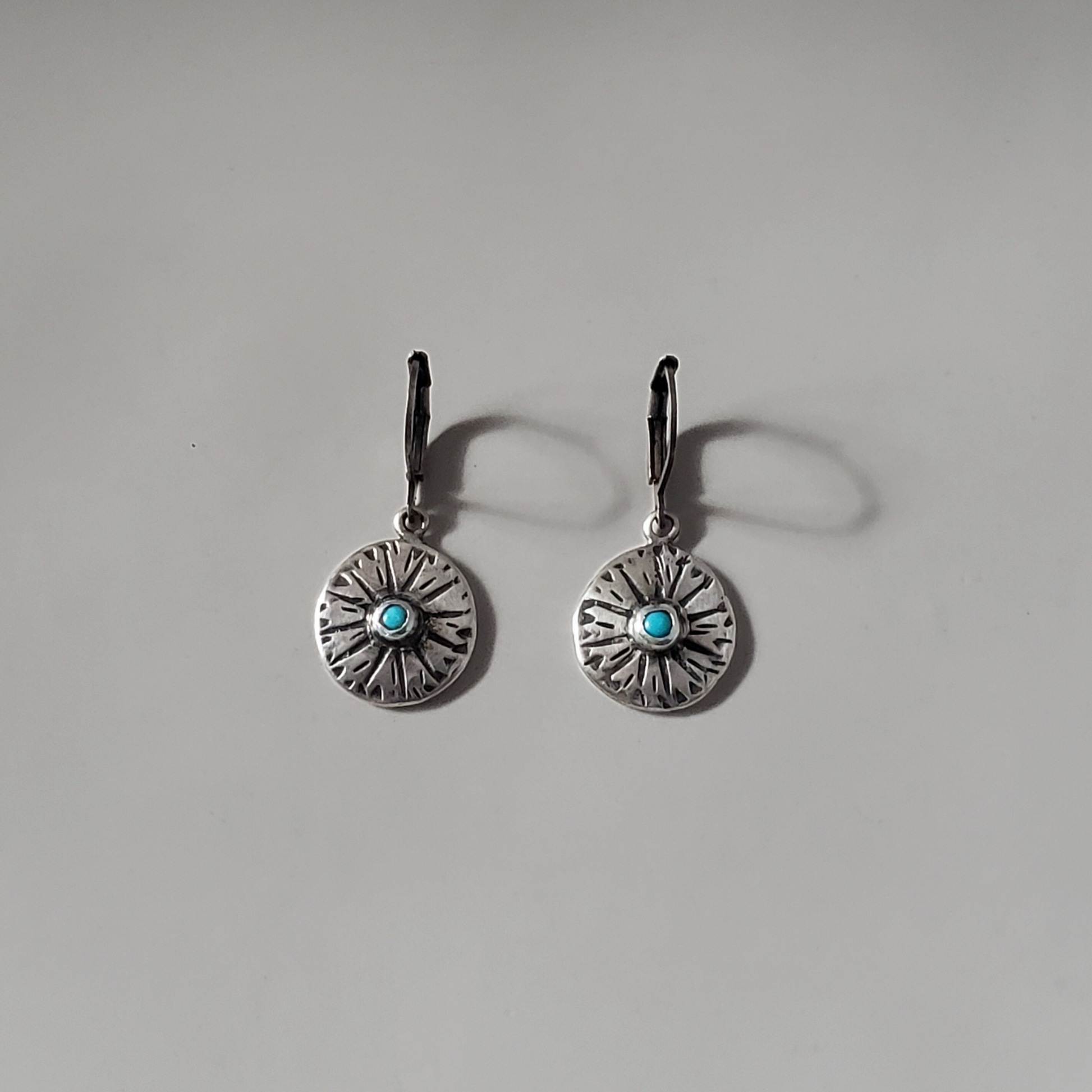 small handmade sterling disc earrings with turquoise gemstone center hung on silver lever backs