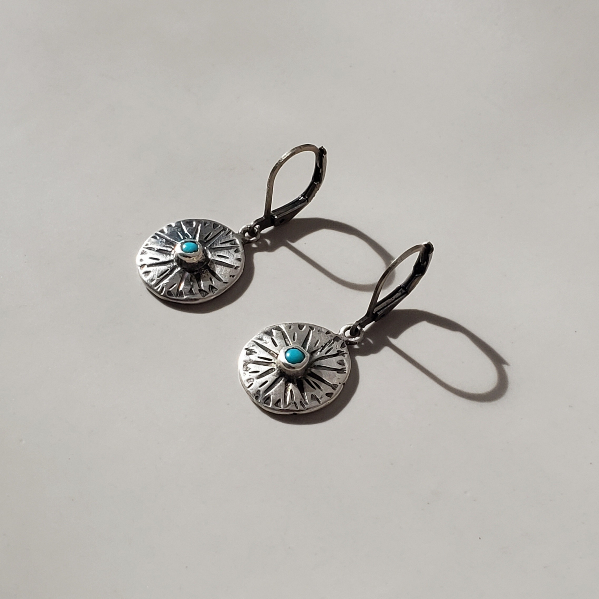 small handmade sterling disc earrings with turquoise gemstone center hung on silver lever backs