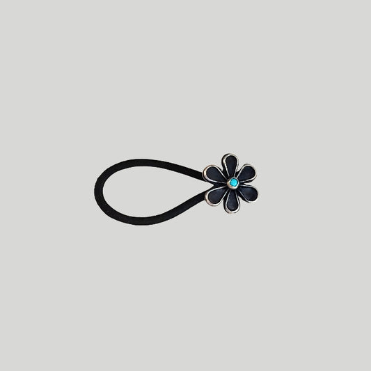 Sterling silver flower with turquoise center attached to a large black hair rubber band. 