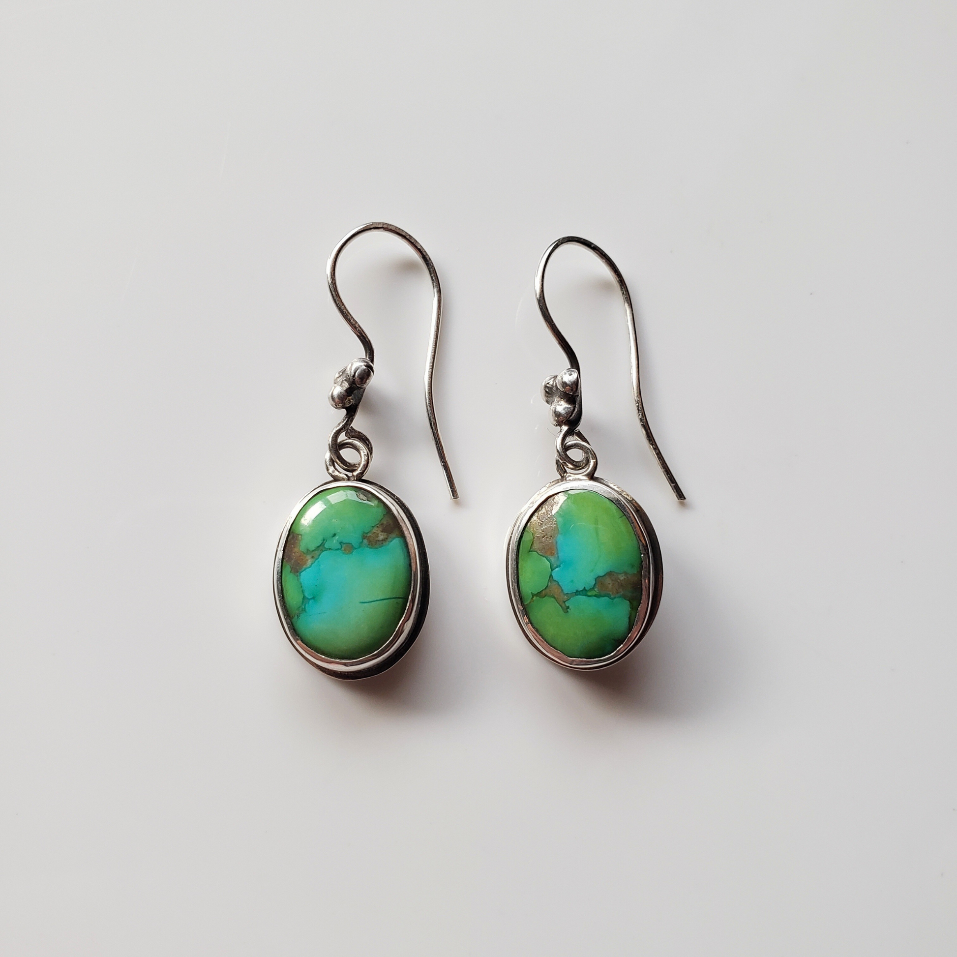 Green blue turquoise earrings against gray background