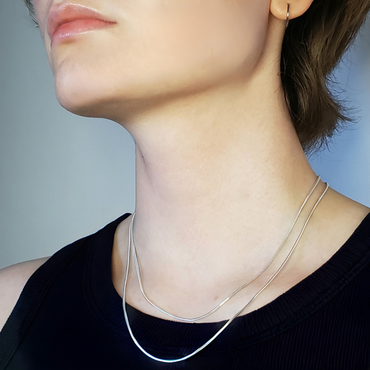 This is an image of a jewelry model wearing two shiny silver snake chain necklace 