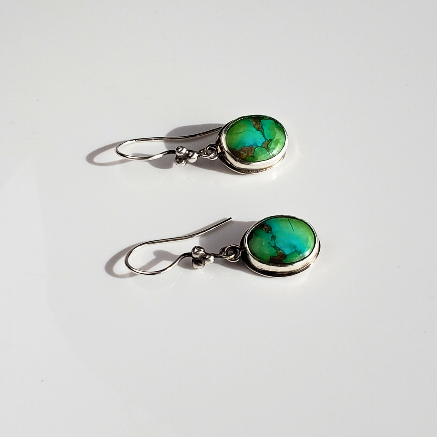 Green blue turquoise earrings against white background