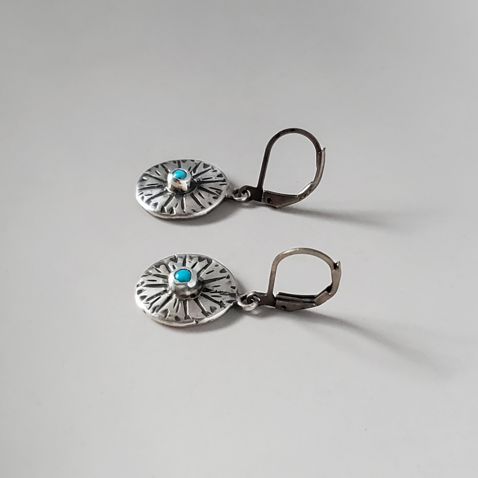 small handmade sterling disc earrings with turquoise gemstone center hung on silver lever backs
