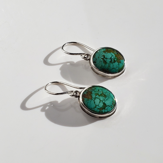 Green turquoise and sterling silver drop earrings against white background