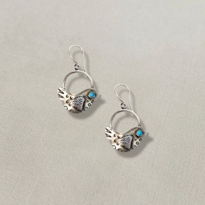 Pair of silver earrings with turquoise stones on a light gray background