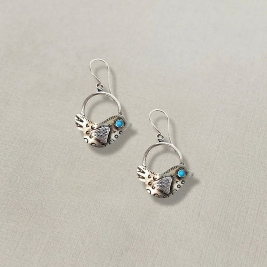 Pair of silver earrings with turquoise stones on a light gray background