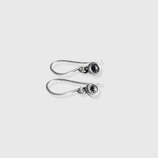 Right facing small silver star earrings hung on silver wires against a gray background. 